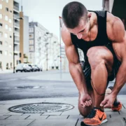 man in workout gear ties his shoes