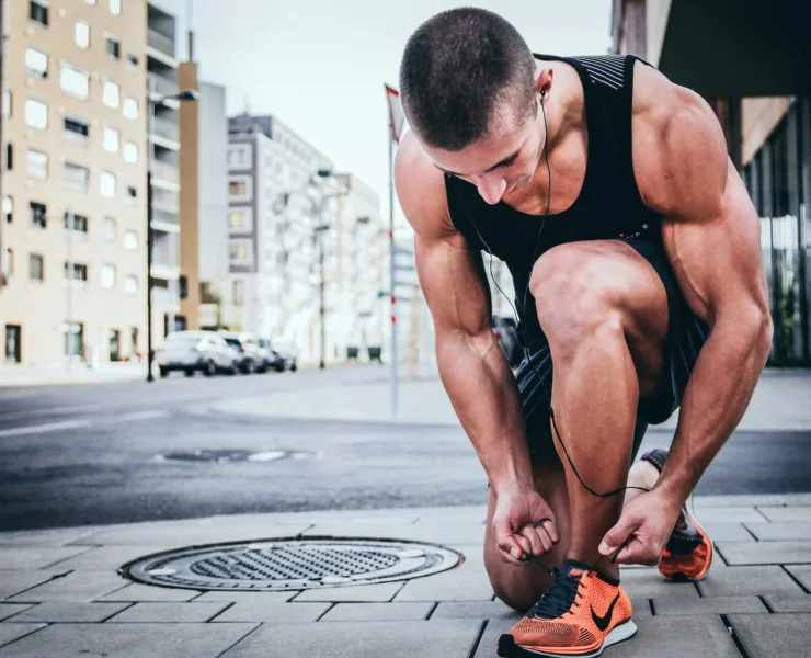 man in workout gear ties his shoes