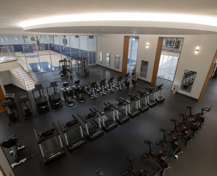 rows of fitness equipment overlook a basketball court