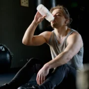 Young man drinking water in the gym