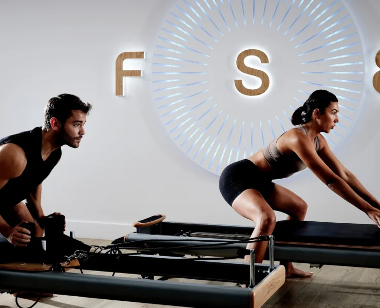 Man and woman on Pilates reformers