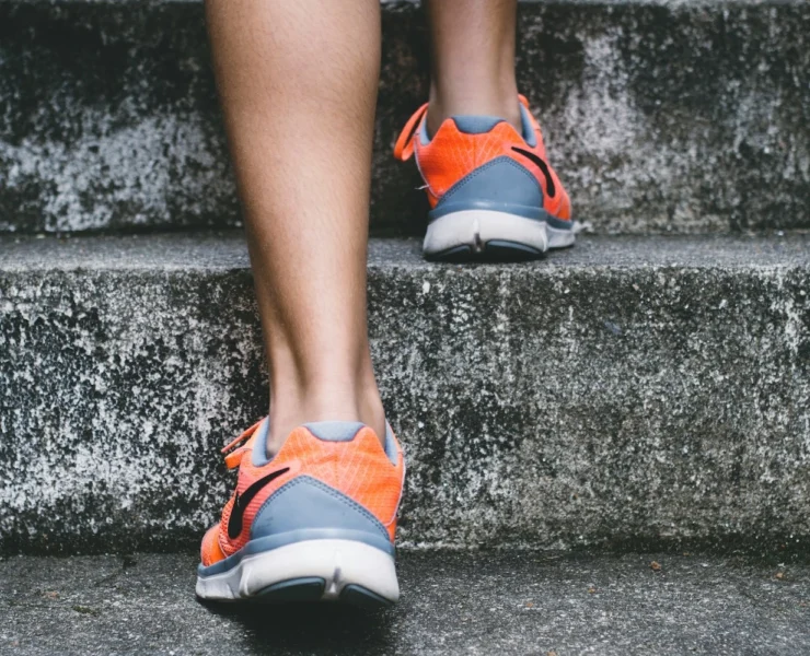 person in sneakers walking up steps