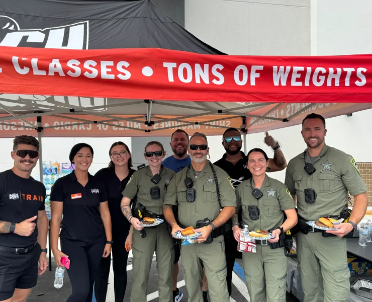 Crunch Fitness staff members and local community members gather in front of a Florida gym