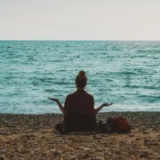 an image of a woman meditating on the beach