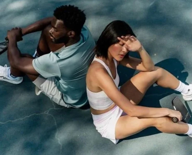 man and woman sitting down on tennis court