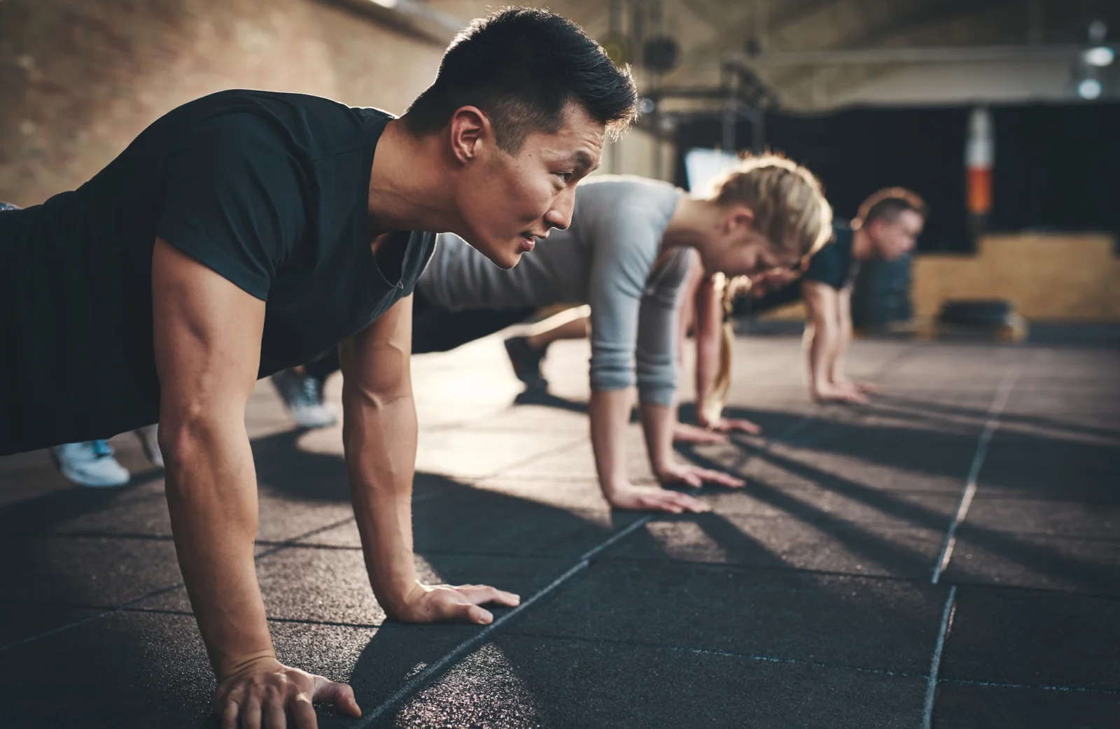 men and women perform planks inside a gym