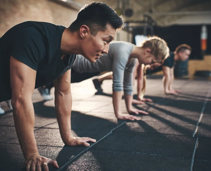 men and women perform planks inside a gym