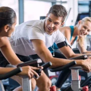 man and two women on indoor cycling bikes