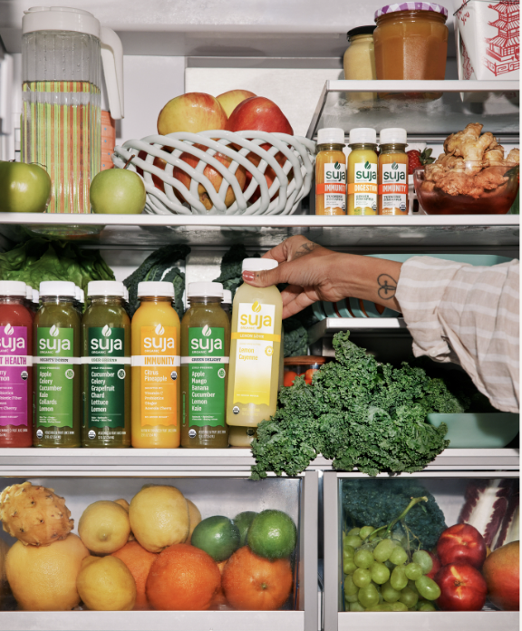 an image of Suja Life's colorful drinks in a frdige with a hand reaching in to grab one